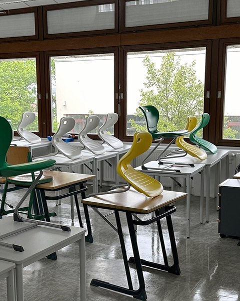 Klassenzimmer mit hochgestellten Stühlen auf den Tischen und frisch gereinigtem, glänzendem Boden.